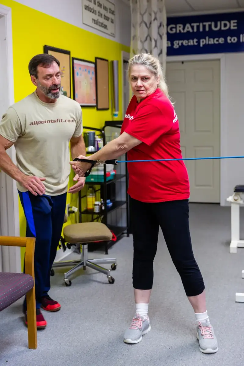 Tim coaching a client in her 60s through a resistance-band row